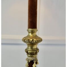 a candle that is sitting on top of a wooden stand with tassels hanging from it