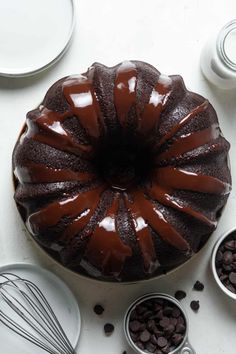 a bundt cake with chocolate icing sitting on top of a table next to other desserts