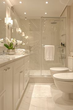 a white bathroom with two sinks, toilet and walk - in shower next to each other