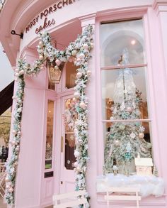 a pink store front with a christmas tree in the window and decorations on the outside