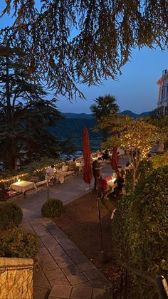 an outdoor patio with tables and umbrellas lit up at night, overlooking the water