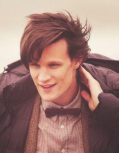 a young man wearing a bow tie and jacket with his hands on his ears while looking at the camera