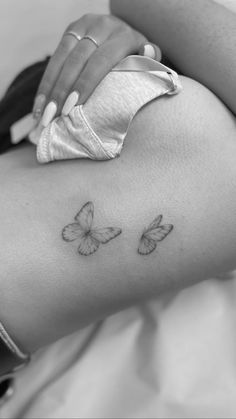 a woman's thigh with two butterflies on the back of her leg, and one is