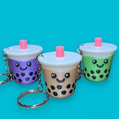 three coffee cups with faces on them are being held by a keychain that is attached to a chain