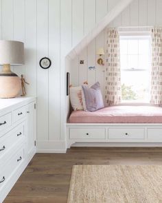 a window seat in the corner of a room with white walls and wooden flooring