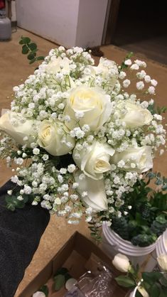 a bouquet of white roses and baby's breath in a vase on a table