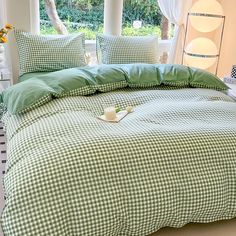 a green and white checkered comforter on a bed in a room with windows