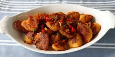 a white bowl filled with fried potatoes on top of a blue and white towel