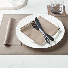 a white plate topped with a fork and knife next to a napkin on top of a table