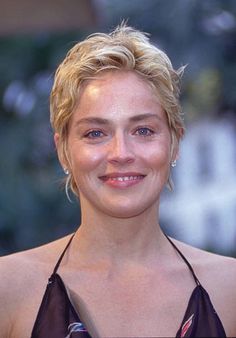 a woman with blonde hair and blue eyes smiles at the camera while wearing a halter top