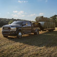 a black ram truck with hay bales in the bed is parked on a grassy field