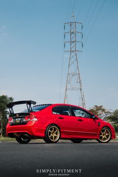 a red car parked next to a power line