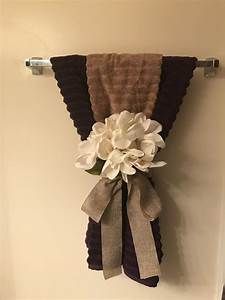 a towel hanging on the wall with flowers attached to it and ribbon around the edge