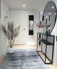 a room with a rug, mirror and vase on the floor in front of it