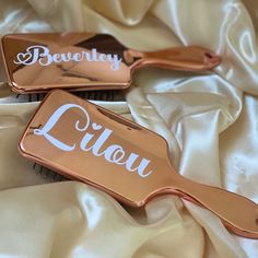 two hairbrushes that are laying on top of a white cloth with the words bevenley and lifou written on them