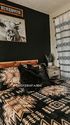 a bed with black and white bedspread next to a painting on the wall