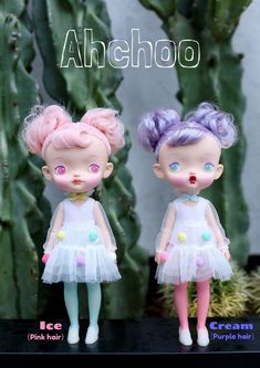 two dolls are standing next to each other in front of cacti and succulents