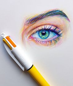 a drawing of an eye with colored pencils next to it on a white surface