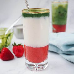 two glasses filled with different colored drinks and strawberries