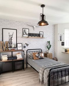 a bedroom with white brick walls and black metal bedspread, wood flooring