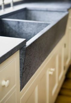 a kitchen sink sitting under a window next to a counter top with drawers and cupboards