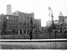 an old black and white photo of a man standing in front of a building