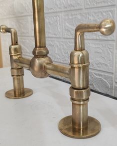 two brass faucets on a white counter top