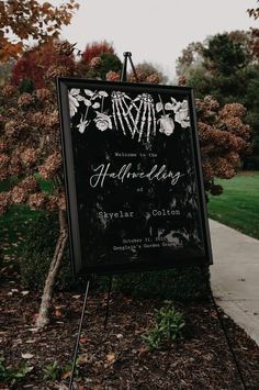 a black and white wedding sign sitting on top of a sidewalk next to a tree