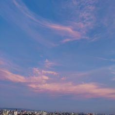 the sky is pink and blue with some clouds in it, as well as buildings