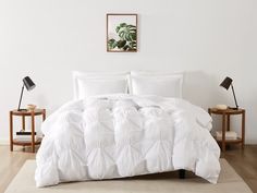 a bed with white comforter and pillows in a room next to two side tables