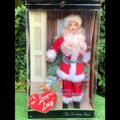 the doll is in its box and has a santa clause on it's chest