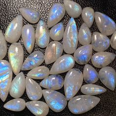 white opalite tears are arranged on a black surface, with some light blue in the middle