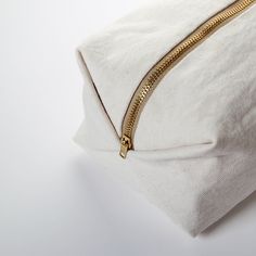 a white pillow with gold zippers on it