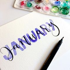 the word january written in cursive writing on a piece of paper next to some watercolor paints