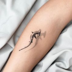 a woman's arm with a small tattoo of a dolphin on the left forearm