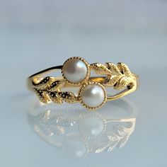 a gold ring with pearls and leaves on it