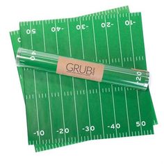 two green football field napkins with the word grub on them and a ruler