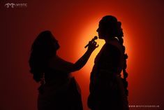 two women are standing in front of a red background and one is holding a microphone