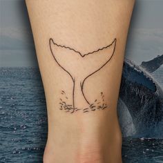 a small whale tail tattoo on the ankle is shown in front of an ocean wave