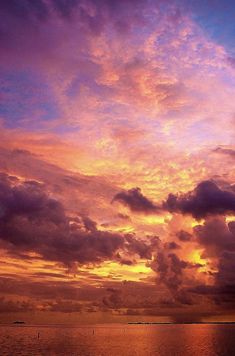 the sun is setting over the ocean with clouds