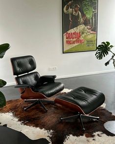 an eames chair and ottoman in front of a painting on the wall with a cowhide rug