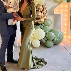 a man and woman standing next to each other in front of balloons