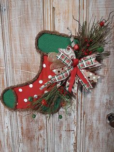 a christmas stocking hanging on the side of a wooden door decorated with red, white and green decorations