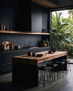 an open kitchen with black walls and wooden counter tops, surrounded by potted plants