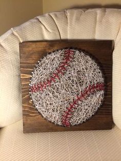 a baseball string art on a wooden frame with red stitching in the shape of a ball