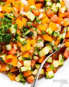 a white bowl filled with chopped vegetables next to a fork