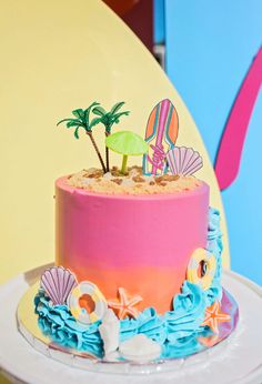 there is a pink and blue cake with palm trees on the top that has been decorated