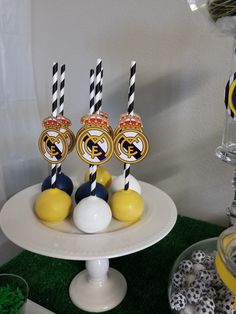 there are three cake pops on the plate with black and white striped straws in front of them