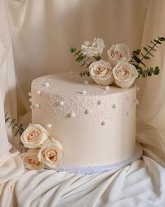 there is a wedding cake with white flowers on the top and pearls on the bottom