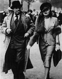 an old black and white photo of two people walking down the street with hats on